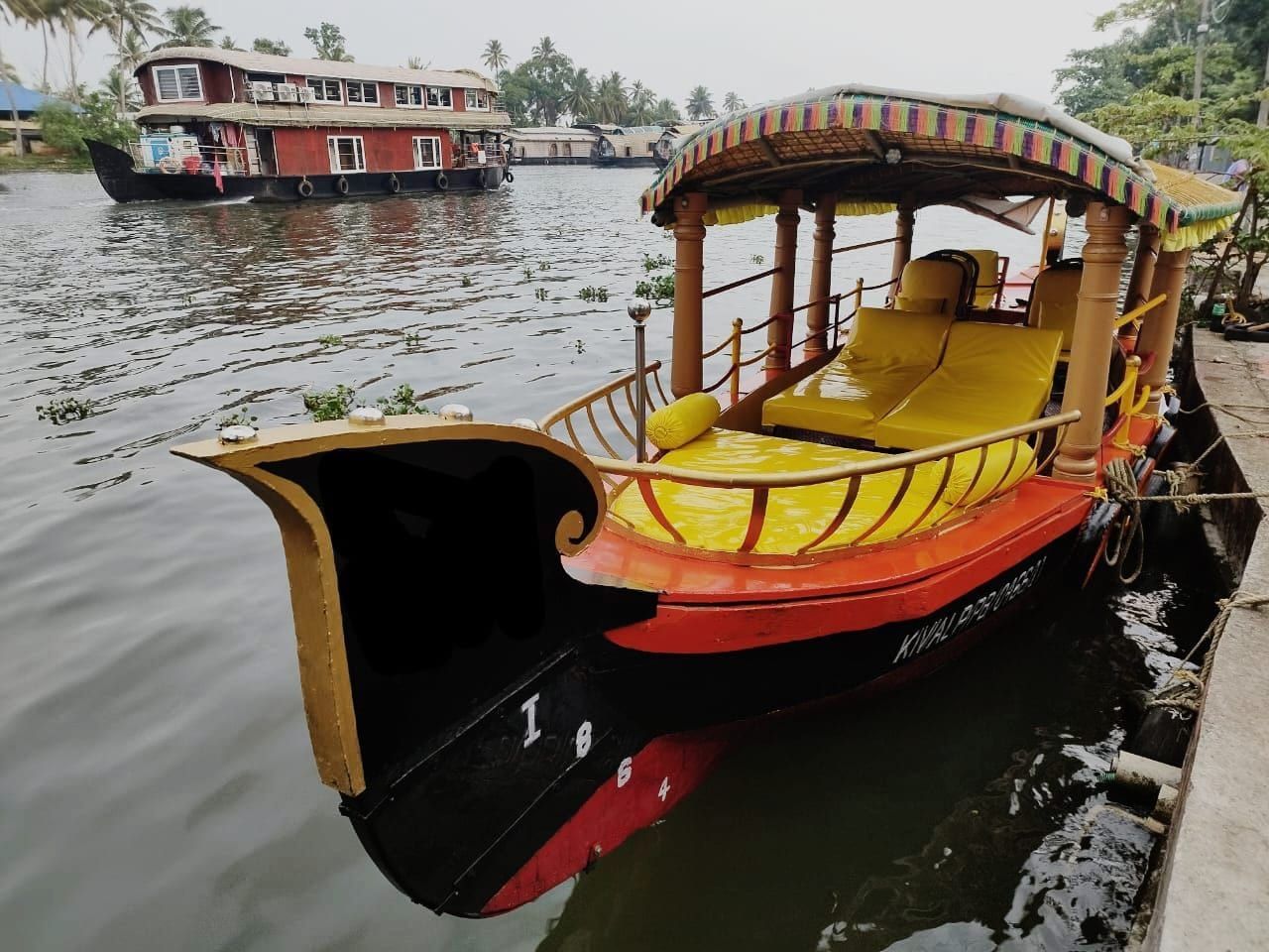 Traditional shikara boat on the Alleppey backwaters with a houseboat in the background